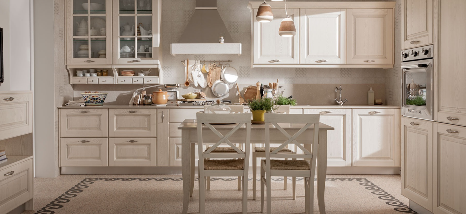 Classic Italian kitchen with cream paneled cabinetry, glass-front display cabinets, built-in appliances, dining table, pendant lighting, and warm traditional styling.