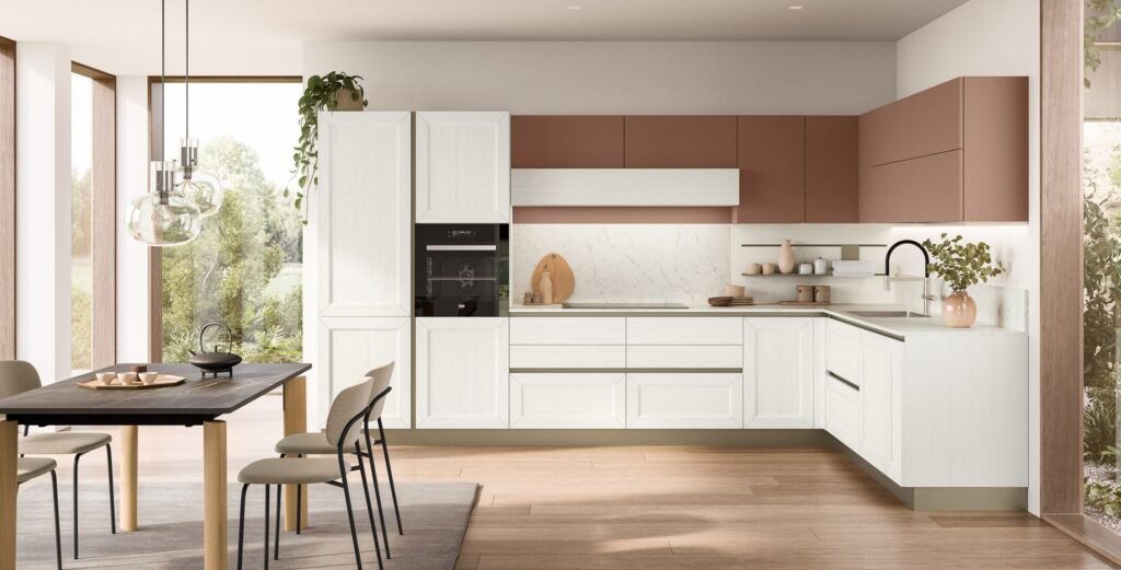 Bright modern Italian kitchen with white shaker-style lower cabinets, terracotta upper cabinetry, integrated appliances, open shelving, marble-look backsplash, wood flooring, and a dining table beside large windows.
